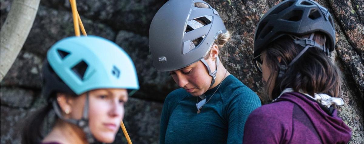 three women wearing climbing helmets