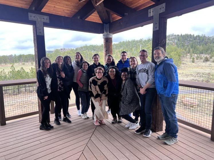 group of graduate students and professors standing on covered porch